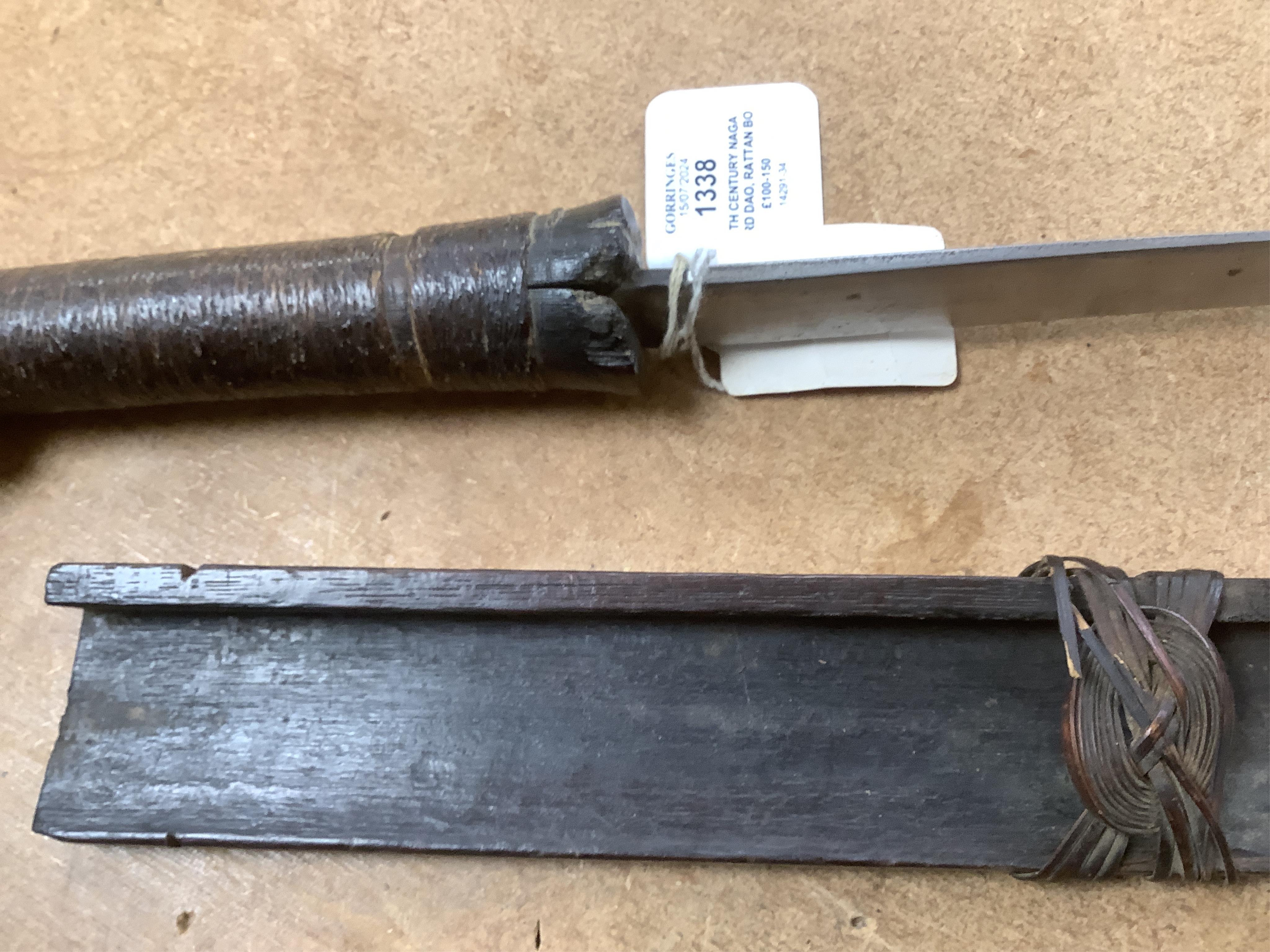 A 19th century Naga sword Dao, rattan bound wooden hilt in its open fronted wooden scabbard, blade 77cm. Condition - fair, some wear overall